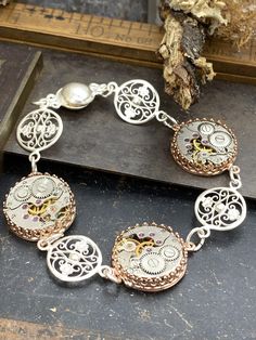 This antique filigree bracelet has three vintage mechanical jeweled watch movements as a base. The beautiful Sterling silver filigree charms are added to the design to give it a vintage flair and the cute magnetic clasp makes it super easy to wear, it can be worn alone or stacked with your favorite collection. This vintage style bracelet makes a great gift idea for your sister, mom or best friend! It is versatile with the combination of element and metallic colors. This bracelet could make a gor Steampunk Silver Watch With Skeleton Dial, Ornate Nickel-free Bracelet, Ornate Nickel-free Bracelet Jewelry, Victorian Style Bracelet With Vintage Charm For Gift, Victorian Bracelets With Vintage Charm As Gift, Silver Steampunk Watch For Formal Occasions, Metal Bracelets With Intricate Design, Victorian Rose Gold Bracelets As Gift, Victorian Rose Gold Bracelets Gift