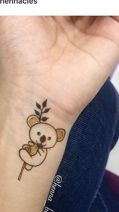 a small tattoo on the wrist of a woman with a koala bear holding a leaf