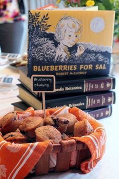 a basket filled with muffins sitting on top of a table next to books