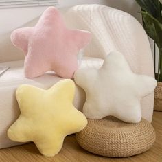 three star shaped pillows sitting on top of a white couch next to a plant in a vase