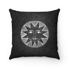 a black and white pillow with an image of a sun face in the middle of it