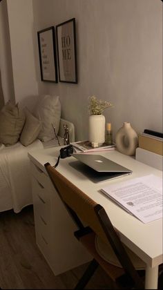 a desk with a laptop computer on top of it next to a bed and pillows