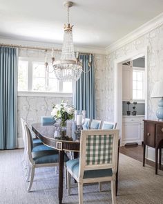 a dining room table with blue chairs and a chandelier hanging from the ceiling