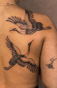 the back of a woman's body with two birds tattooed on her upper half