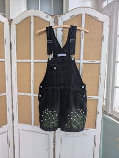 Delicate little chamomile flowers crawl up the legs of these black denim overalls. Another small sprig sticks out of the back pocket. Somewhere between cottagecore and whimsy goth, perfect paired with a black and white striped T-shirt. Upcycled denim in very good condition. Teen or youth size 7/8. 13 inches across the chest, 15 inches across the waist. 19 inches across the hips. 23 inches long. Black Short Overalls Outfit, Shorts Overalls Outfit, Leah Core, Black Short Overalls, Black Denim Overalls, Denim Overall Shorts, Shorts Overalls, Chamomile Flower, Whimsy Goth