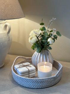 a white vase filled with flowers sitting on top of a table next to a candle