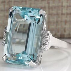 an aqua blue topazte and diamond ring on a white surface with a basket in the background