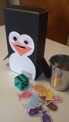 a penguin and some dices on a table with a box in the shape of a cube