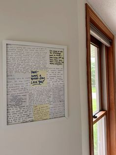 a framed piece of paper with writing on it next to a window in a room