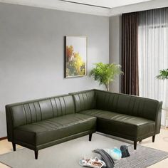 a living room with a green leather sectional couch and rugs on the floor in front of a window