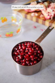 pomegranates in a metal bowl on a white counter top next to other food items