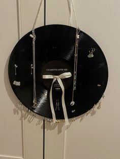 a black record with white ribbon hanging from it's side and jewelry attached to the disc