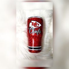 the kansas chiefs glitter tumbler is sitting on a furry white surface with it's logo