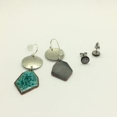 This earring set includes one pair of dangle earrings and one pair of stud earrings. The colored pieces of these earrings are made with enamel which is a technique that fuses glass to a metal surface. The dangle earrings have sterling silver wires with rubber stoppers, and measure 1 1/2 inches long. The stud earrings have stainless steel posts and measure 1/4 inch in diameter. Your purchase will come shipped in a brown paper gift box. Blue Hammered Drop Earrings, Blue Hammered Earrings For Gift, Soldered Enamel Drop Earrings, Copper Paper, Blue Enamel Earrings, Enamel Stud Earrings, Paper Gift Box, Metal Surface, Hammered Metal