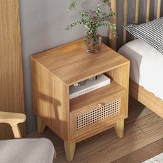 a small wooden nightstand with a plant on it next to a white bed and chair