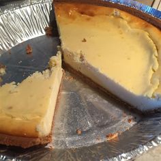 a cheesecake sitting on top of a tin foil covered pan with one slice cut out