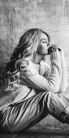 a black and white photo of a woman sitting on the floor with her hands in her mouth