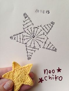 a hand holding a small yellow star shaped cookie in front of a white piece of paper with words written on it