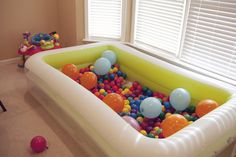 an inflatable bathtub filled with lots of balls and plastic toys on the floor