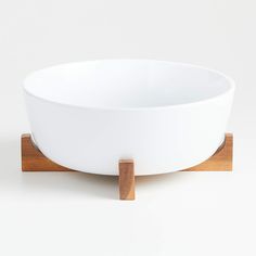 a white bowl with wooden stand on top