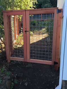 a gated in area with plants and dirt on the ground next to an open door