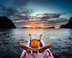 a person in a kayak paddling towards the sunset