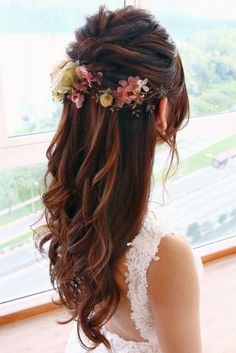 a woman with long hair and flowers in her hair is looking out the window at something outside