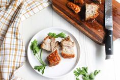 some meat is on a white plate with parsley next to it and a knife