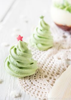 two cupcakes with green frosting and a red star are on a doily