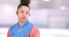 a woman with a bun in her hair wearing a blue and orange top is looking at the camera