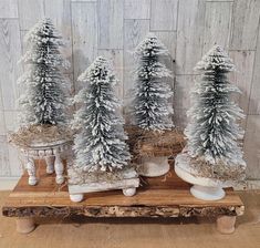 three white christmas trees sitting on top of a wooden table