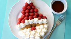 a white plate topped with a piece of cake covered in whipped cream and raspberries