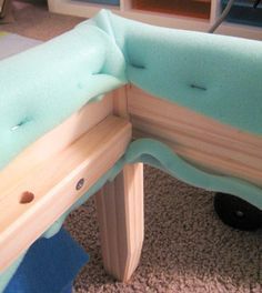 a close up of a wooden bench with blue cushions on the top and bottom part