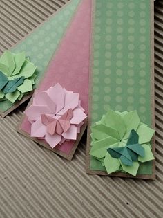 three folded paper flowers sitting on top of a cardboard box