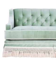 an upholstered green velvet couch with tassels