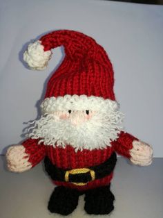 a knitted santa clause doll is posed on a table