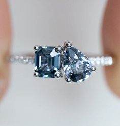 a woman's hand holding an engagement ring with two blue stones