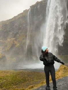 a woman standing in front of a waterfall