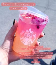 a person holding up a pink drink in their hand