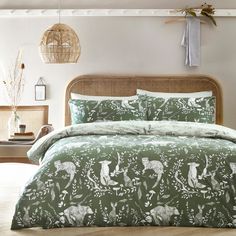 a bed with a green comforter and white sheets on it in a room next to a wicker basket