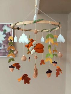 a mobile made out of felt with leaves and acorns hanging from the ceiling