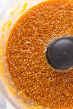 a food processor filled with orange sauce and brown stuff in it's bottom layer