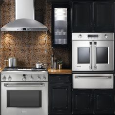 a modern kitchen with stainless steel appliances and wood counter tops, black cabinets, and tile backsplash