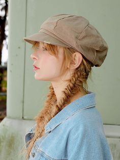 a woman wearing a hat with braids in her hair and looking off to the side