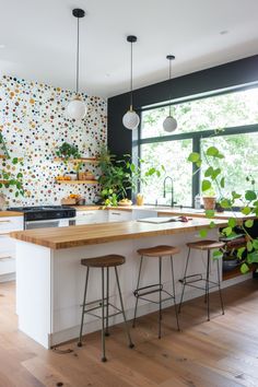 a kitchen with two stools in front of an island and potted plants on the counter