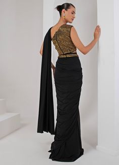 Introducing the stunning Black Pre-Draped Saree Set, crafted from luxurious lycra and crepe. This elegant black saree features beautifully pleated pallu detailing that creates a sophisticated drape, effortlessly merging modern convenience with the timeless grace of traditional attire. Paired with a chic sleeveless blouse, showcasing a contemporary one-shoulder neckline and adorned with intricate nalki embellishments that add a subtle shimmer. A hand-embellished belt cinches the waist, providing a stylish accent that perfectly ties the look together. Ideal for cocktails or high-end parties, this saree ensures you make a statement with its unique fusion of tradition and trend. Composition : Blouse - Crepe blend & Saree - Lycra Care: Dry Clean Only and Vacuum Storage This product can be custo Draped Saree, Embellished Belt, Vacuum Storage, Drape Saree, Indian Wedding Wear, Black Saree, Traditional Attire, Wedding Wear, Sleeveless Blouse