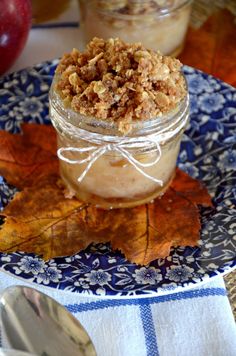 an apple pie in a jar on a blue and white plate with autumn leaves next to it