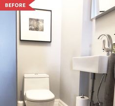 a white toilet sitting next to a bathroom sink under a framed picture on the wall