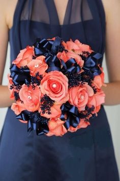 a woman in a blue dress holding a bouquet of orange and black flowers on her wedding day