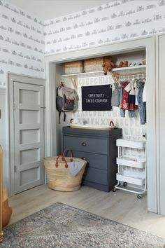 a baby's closet with clothes hanging on the wall and a basket in front of it